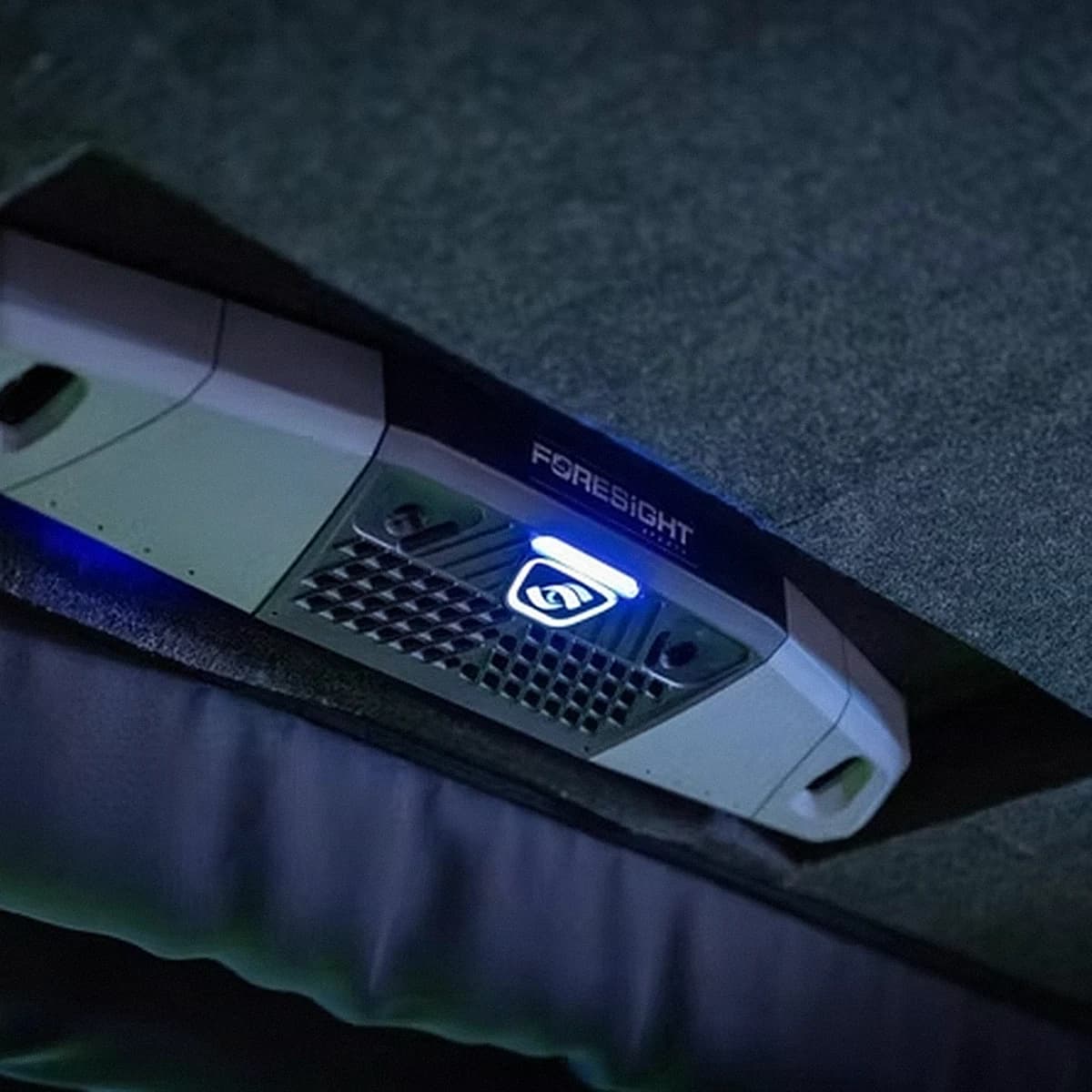 Foresight Falcon launch monitor mounted overhead at That Golf Place, illuminated logo and blue LED against the bay ceiling