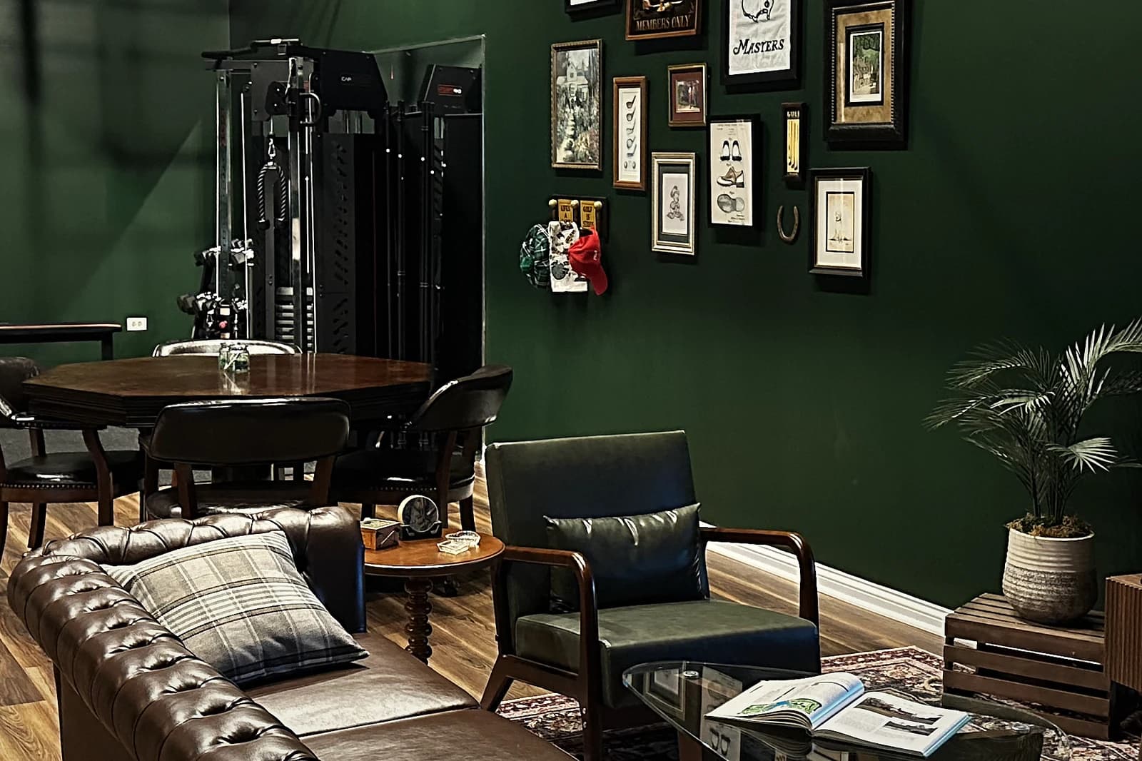 Lounge at That Golf Place with chesterfield sofa, green leather chair, gallery wall of vintage golf prints, patterned rug and wood card table